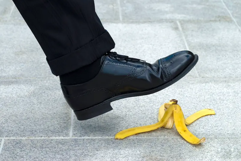 Man slipping on banana peel on the sidewalk